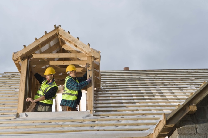 Construction workers building the roof of a house