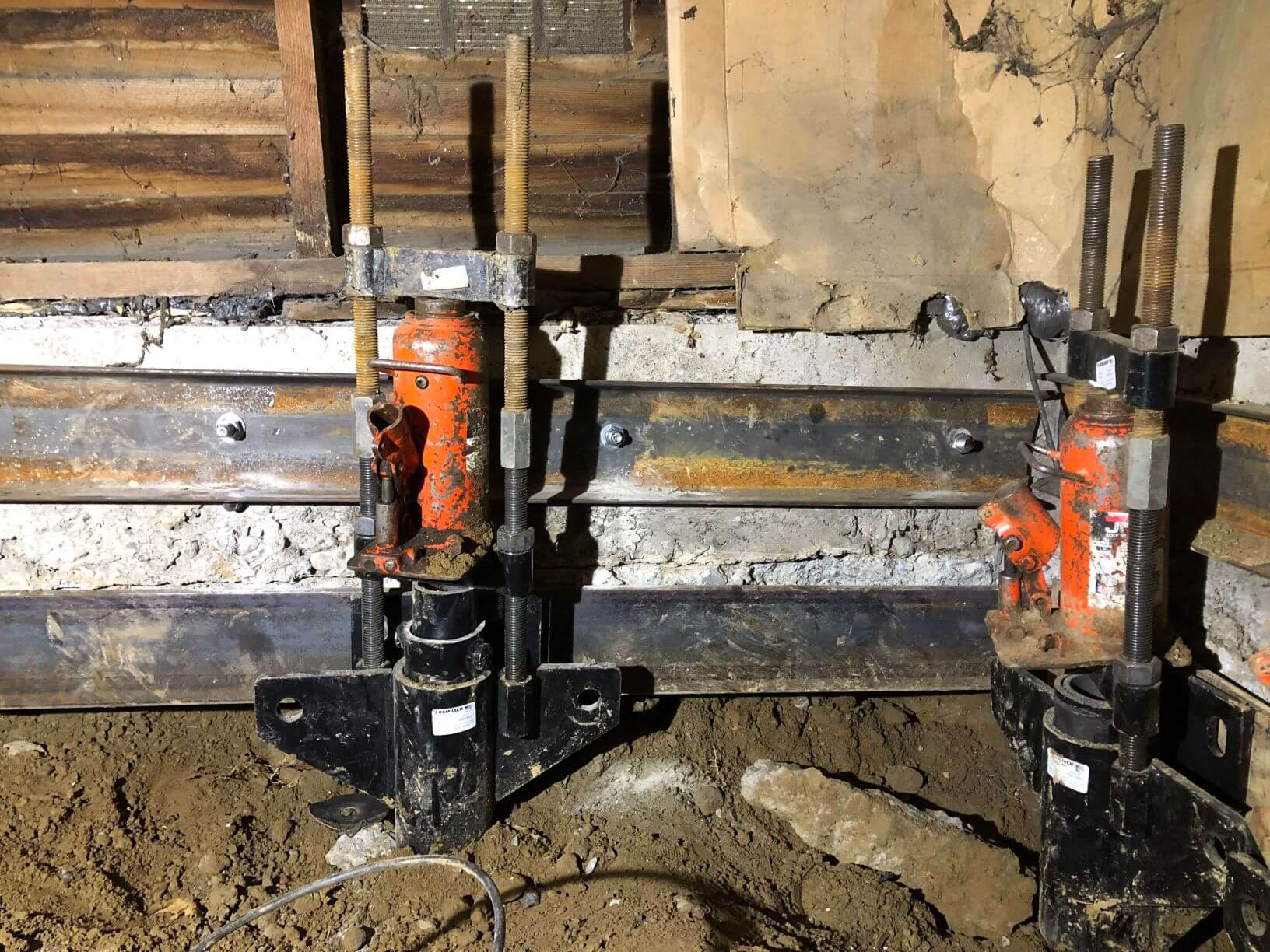 two driven piles being installed in a crawlspace
