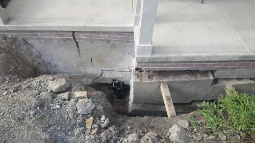 excavated area revealing damage to foundation under a porch